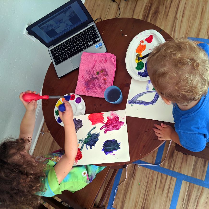 Inclusive Arts Vermont
Image of two toddlers looking from above, as they paint with colorful paints while following instruction from a laptop computer screen.