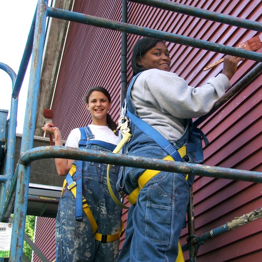 Vermont Works for Women
Two young women painting the siding of what appears to be a big red barn.